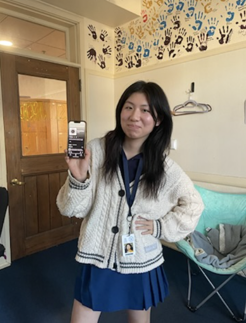 Betti Pang ‘23 shows off her podcast profile in the Senior Lounge, wearing her Taylor Swift cardigan.