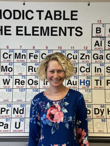Mrs. Davis poses in front of the periodic table in her chemistry room.