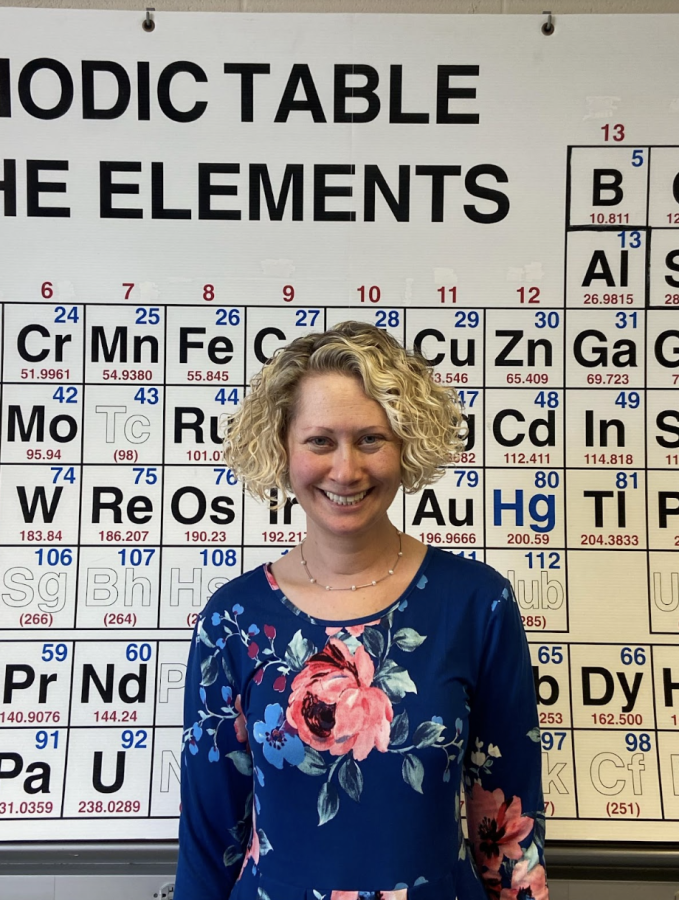 Mrs.+Davis+poses+in+front+of+the+periodic+table+in+her+chemistry+room.